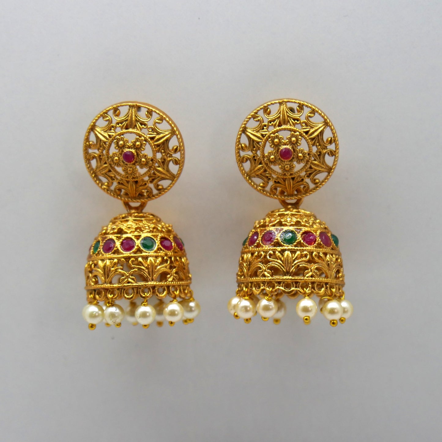 earrings with intricate designs and colored gemstones on a light gray background